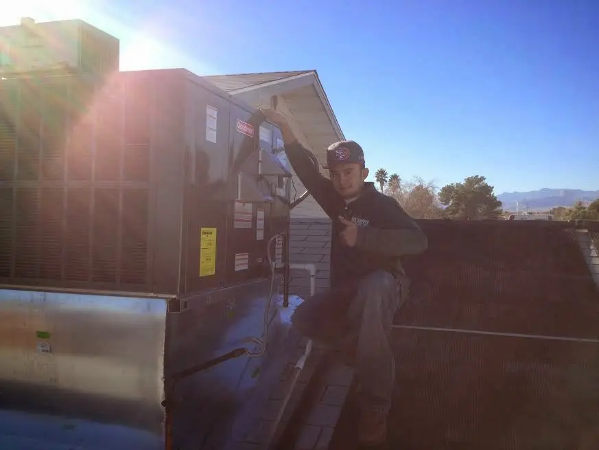 HVAC technician performing AC Tune-Up on a rooftop unit in Winchester